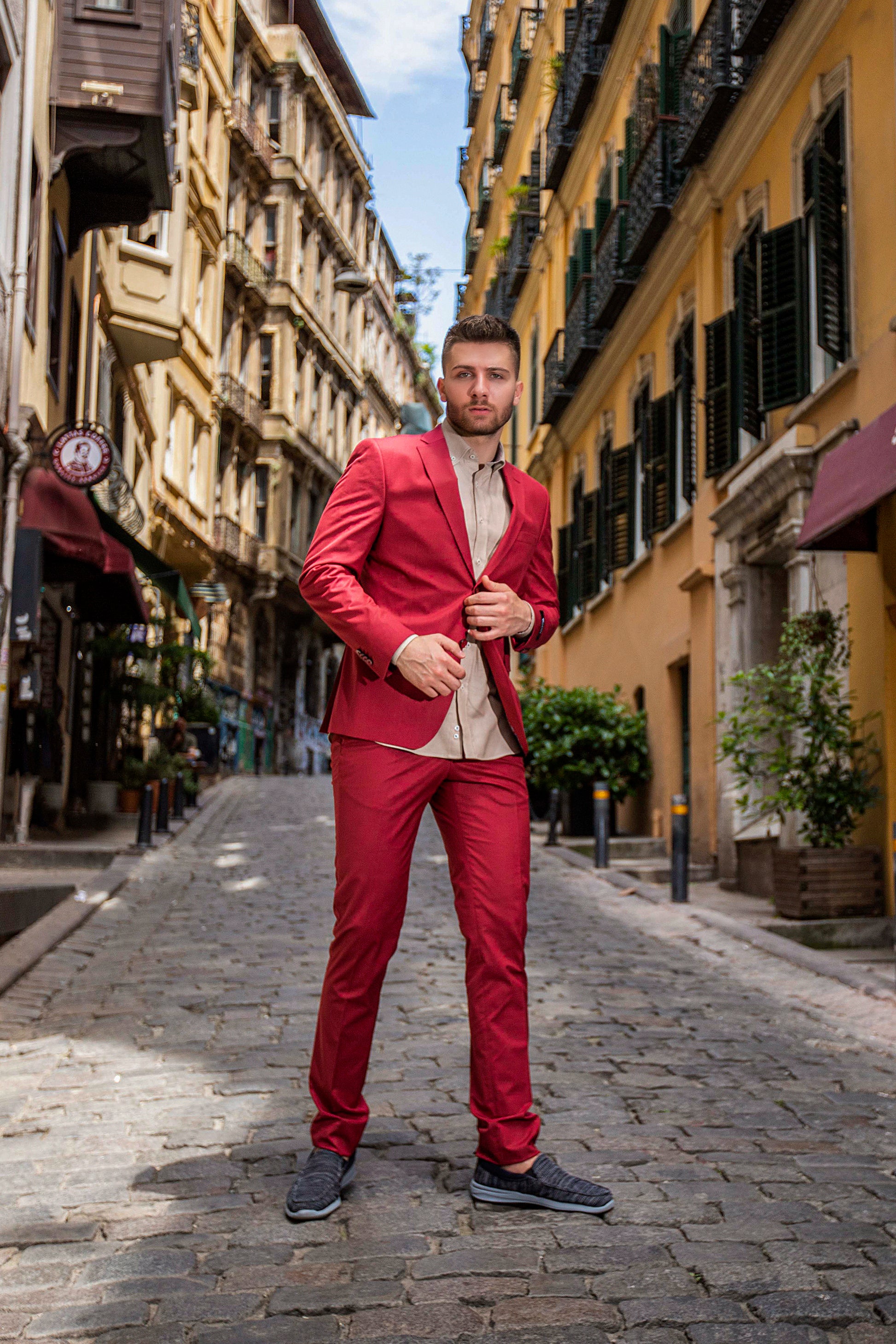 Bold-Red, Slim-Fitted suit made with premium-blended wool, red buttons, and notched lapel. Model is wearing a complementing slim, beige shirt.