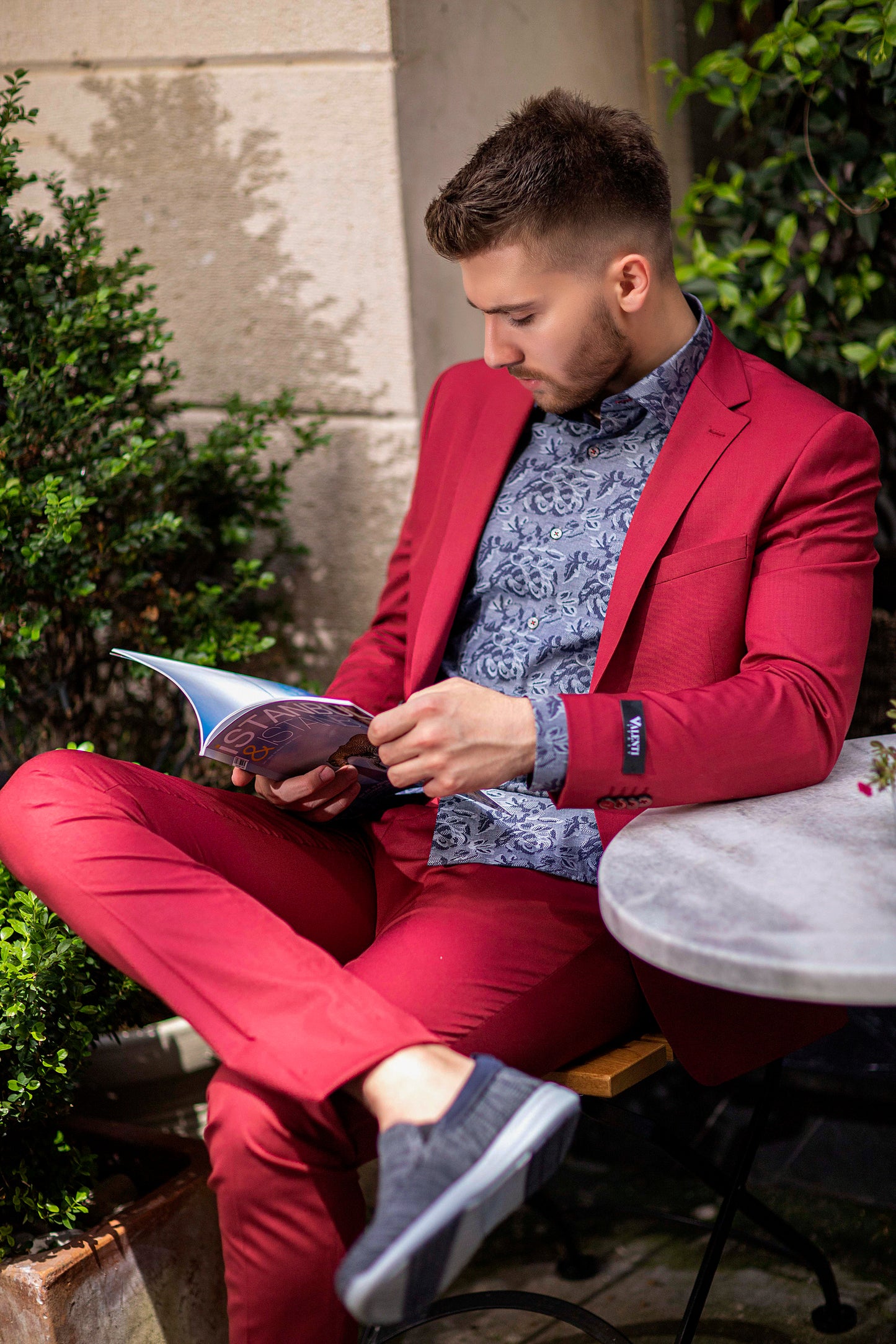 Bold-Red, Slim-Fitted suit made with premium-blended wool, red buttons, and notched lapel. Model is wearing complementing navy, fern-design, slim Valenti Shirt